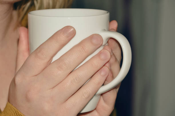 Close up of hands holding a white coffee cup