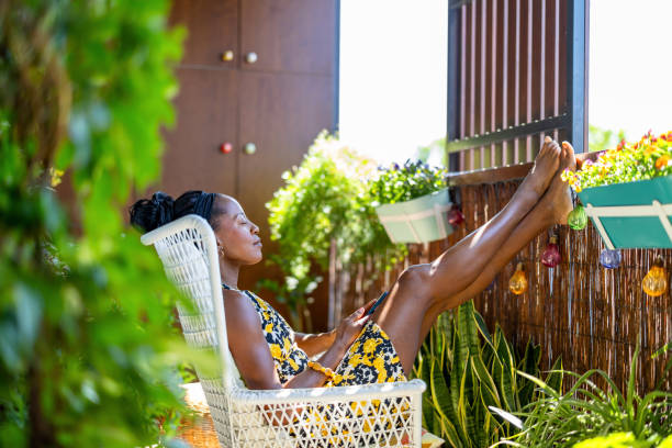 Beautiful woman using mobile phone while relaxing on the balcony at home
