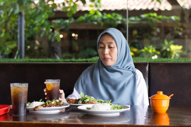 istock A young woman in a hijab enjoys lunch at a restaurant 2158619607