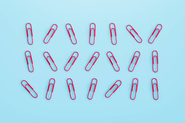 Red stapler with staples on yellow background, flat lay