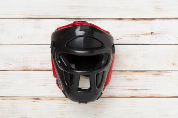 Black leather boxing helmet on wooden background, top view.