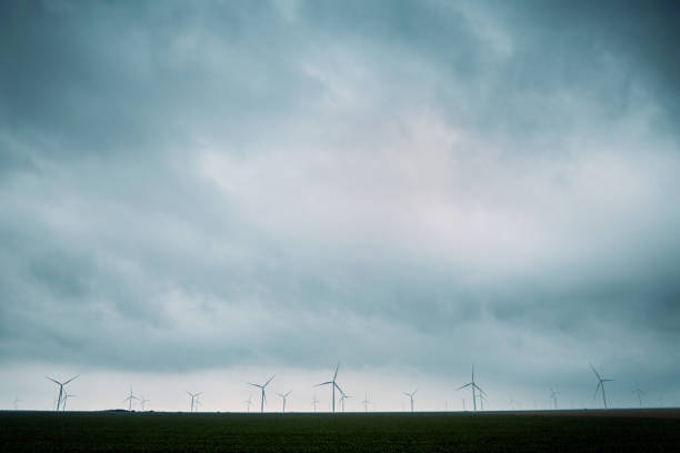 Wind turbines tower above the earth in a rural setting, drawing renewable energy as they spin. Sustainable energy and green technology that considers the environment.   Shot in Texas, USA.
