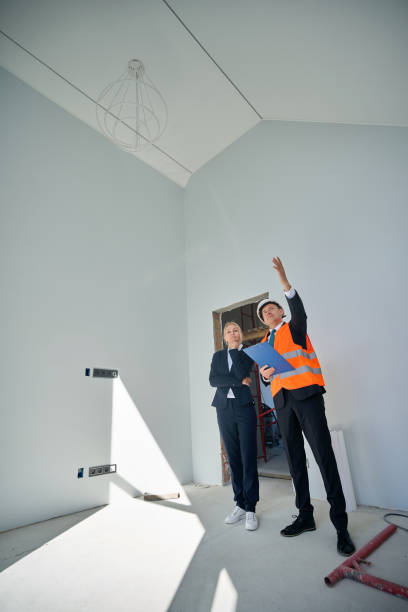 istock Female client and male architect standing in empty room 2158653621