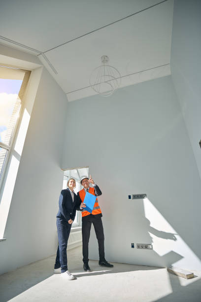 istock Businesswoman and engineer standing while having room inspection 2158653628
