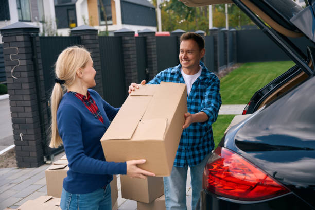istock Joyful couple standing and unloading boxes out of car trunk 2158653713