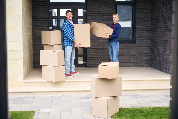 istock Cheerful wife and husband standing on porch while holding boxes 2158653717