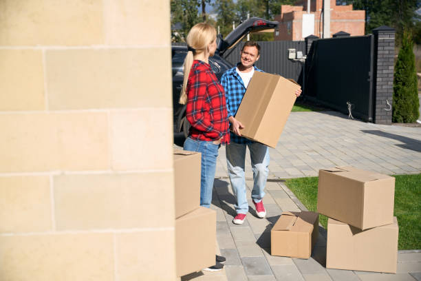 istock Woman standing on doorstep while man carrying cardboard box 2158653734