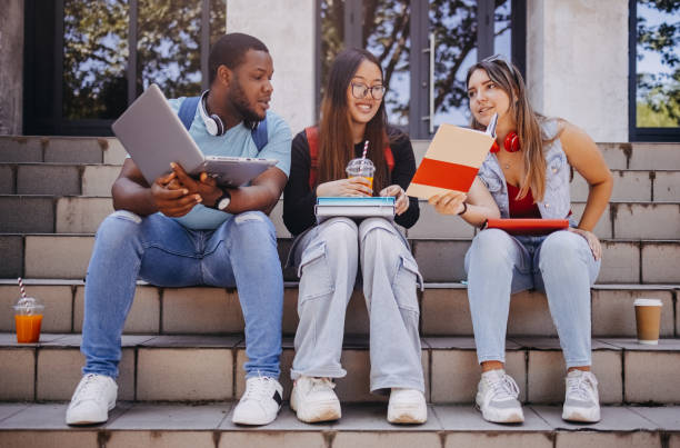 istock Multiracial group of students in front of University after class looking at book 2158653988