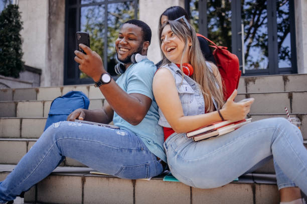 istock Multiracial group of students sitting in front of University after class using mobile phones 2158654016