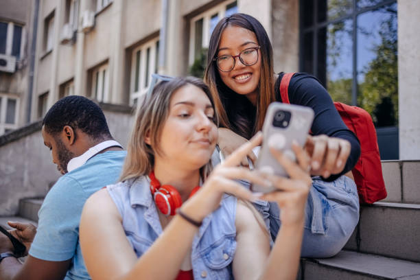 istock Multiracial group of students sitting in front of University after class using mobile phones 2158654024