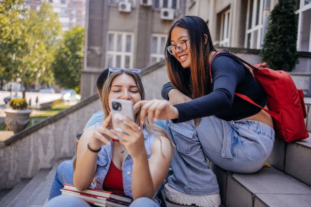 istock Multiracial group of students sitting in front of University after class using mobile phones 2158654025