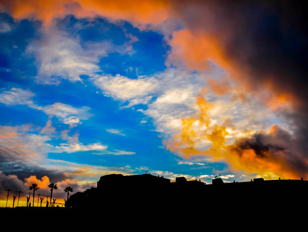 A beautiful sunset with a blue sky and orange clouds. The sky is filled with clouds and the sun is setting