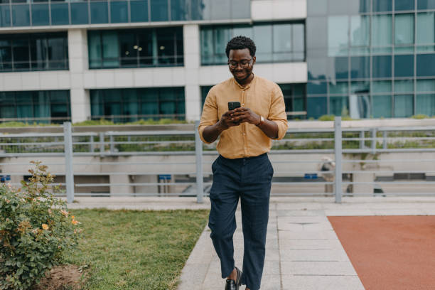 istock Man walking and holding a smartphone outdoors 2158655624
