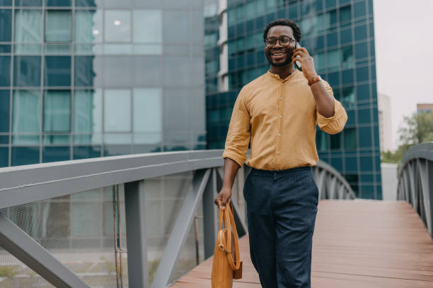 istock Man in yellow shirt talking on phone, walking bridge 2158655695