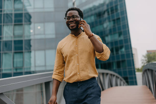 istock Smiling man on the phone, walking over bridge alone 2158655699