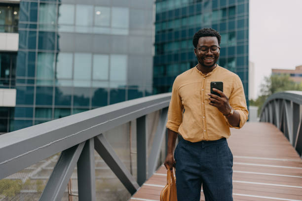 istock Man with tan bag smiling while looking at phone bridge 2158655725