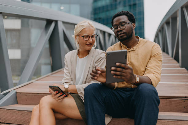 istock Man showing tablet to woman on stairs,both smiling 2158655744