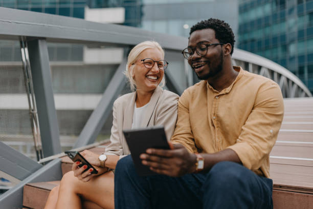 istock Laughing friends on steps with tablet and smartphone 2158655769