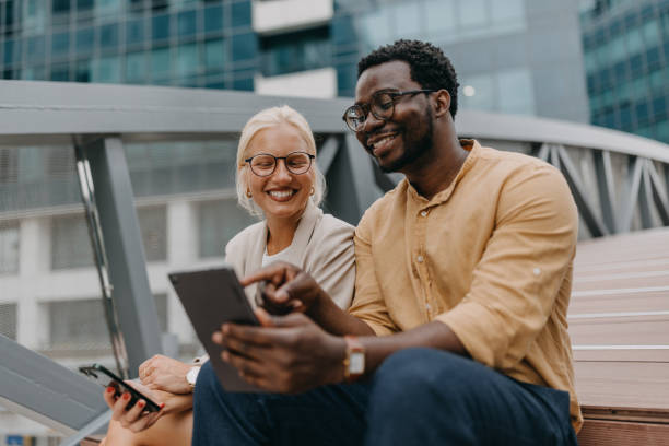 istock Smiling duo interacting with a tablet and smartphone 2158655792