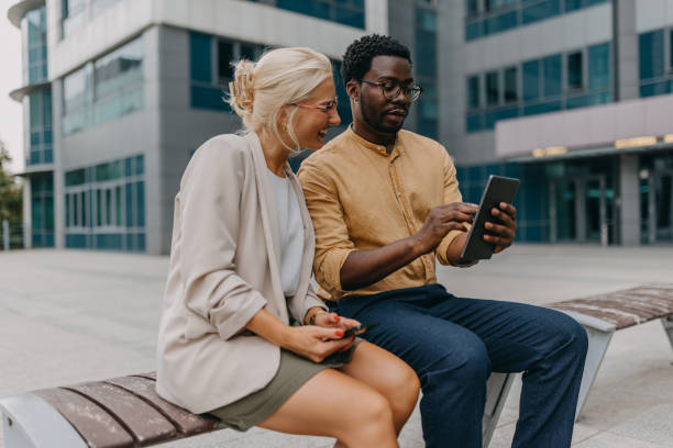 istock Colleagues share screen, collaborating on outdoor bench. 2158655863