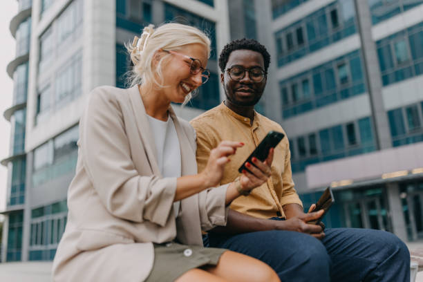 istock Colleagues sharing smartphone, enjoying outdoor time. 2158655880