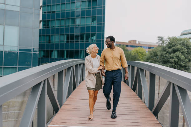 istock Smiling colleagues walk across bridge in urban area. 2158655889