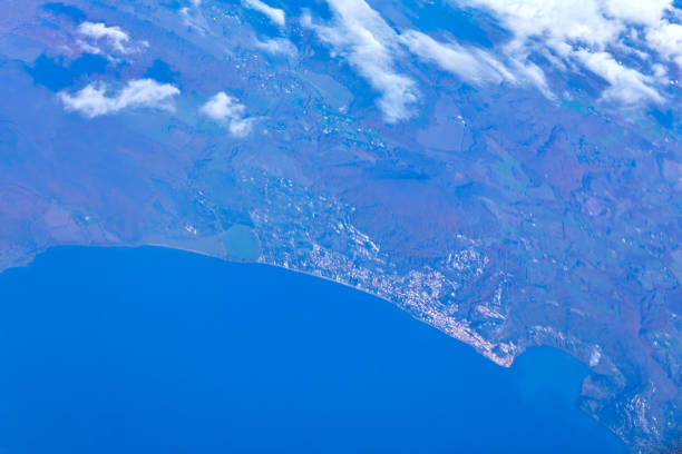 Plane soaring above a vast body of water. Scenic aerial shot of sea and land