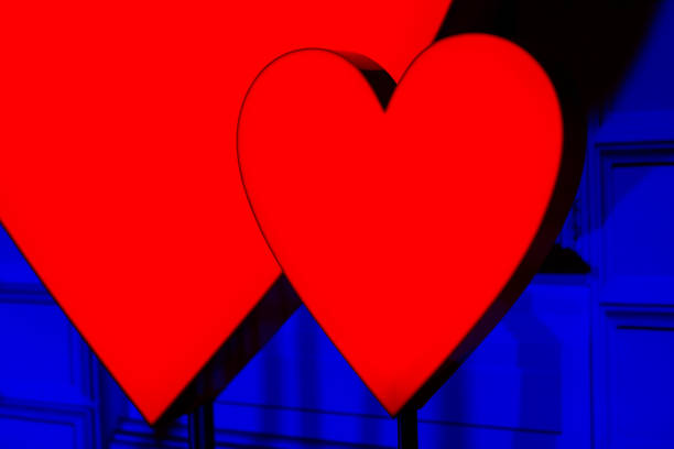 Red hearts are lit up in a blue background. . The hearts are close to each other and appear to be glowing. Symbol of love and affection