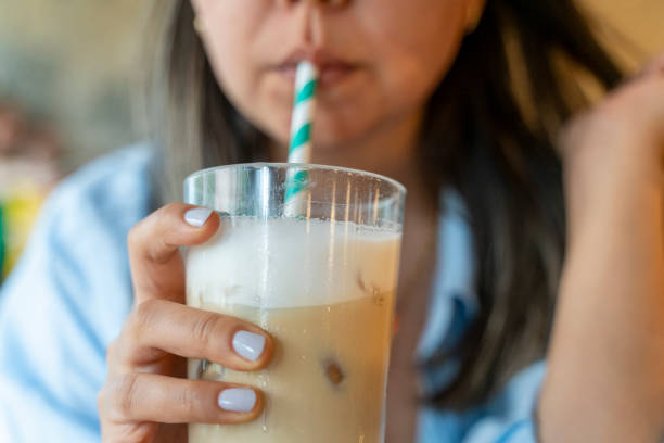 The woman drinks coffee with cold milk. There is a straw in the glass. woman drinking latte coffee.