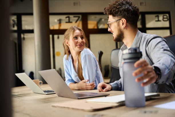 istock Businessman and businesswoman looking at each other while working 2158659843