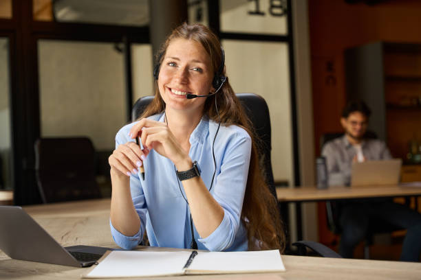 istock Smiling female call center operator looking at camera near blurred colleague 2158659871