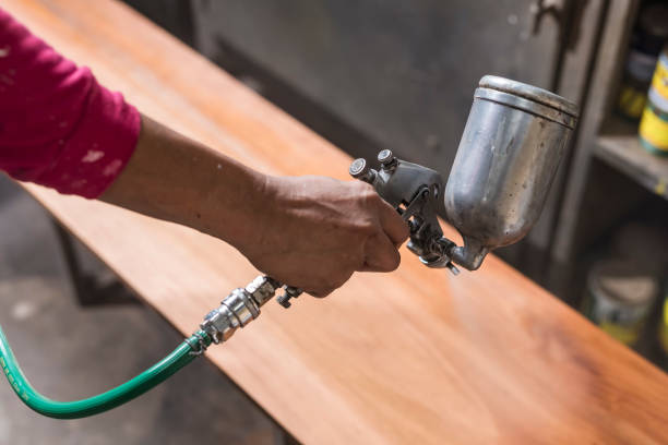 istock A handyman sprays lacquer wood finish on a bench or table. Using an airbrush for the application. At a furniture and woodworking shop. 2158669354