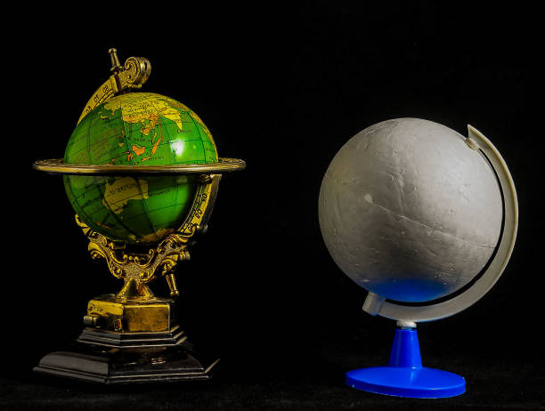 istock Two globes, one green and one white, sit on a black background 2158669846