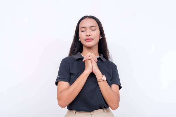 istock A devout young woman solemnly prays to a higher power. A pious lady on a white background. 2158672788