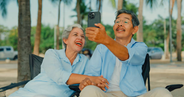 istock Asian elderly cheerful couple smiling while using smartphone video call with family on vacation. A happy senior adult people enjoy the travel lifestyle after retirement. 2158674816