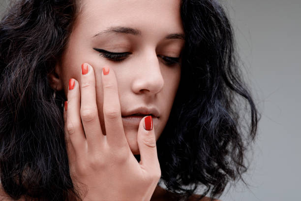 istock Sad woman touching her face with red nail polish 2158675125