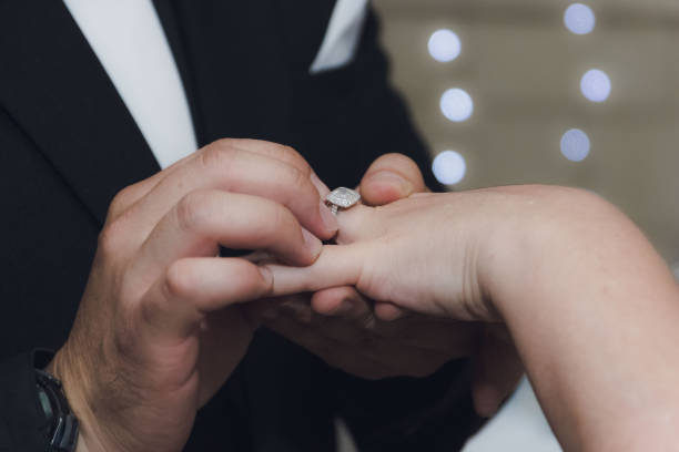 THE GROOM PLACES THE WEDDING RING ON HIS BRIDE ON HER FINGER