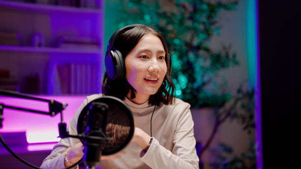 Young Asian woman opening visual aids while talking to audience during a podcast session. stock photo