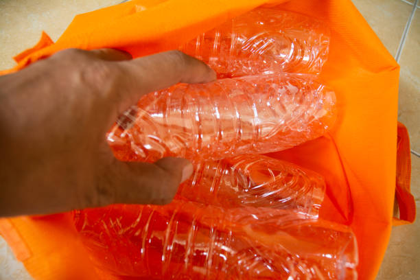 A close-up image of a hand picking up and sorting plastic bottles for recycling. This stock photo represents environmental awareness, waste management, and sustainability efforts. Ideal for content related to eco-friendly practices, plastic waste reduction, and global recycling initiatives.