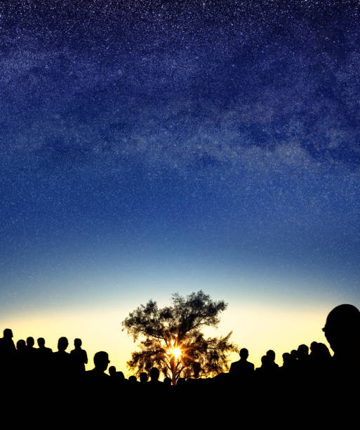 istock Large single tree, crowd of people over sky with stars during sunset 2158688592