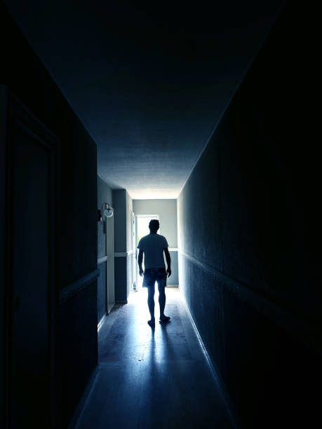 istock Single man walking at dark narrow corridor in to glowing light 2158688655