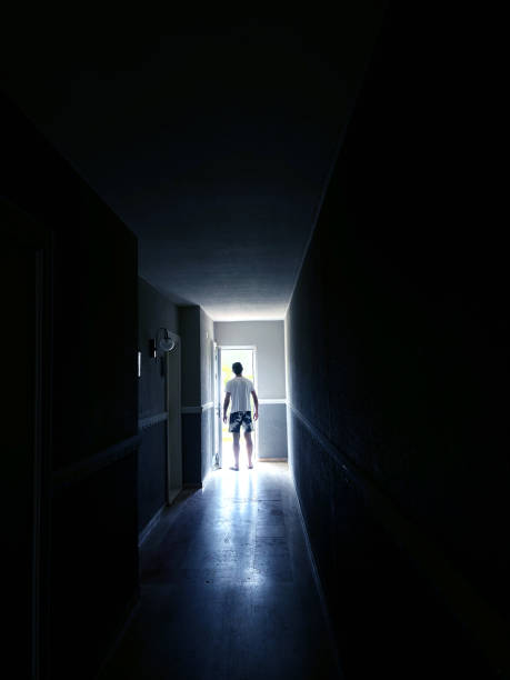 istock Single man walking at dark narrow corridor in to glowing light 2158688669