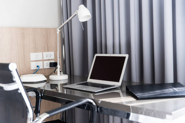 Home office interior desk with laptop computer, Modern cozy work space. Business working decorated room stylish clean new furniture at windows curtain.