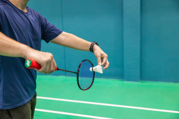 istock Badminton player hand serving holding shuttlecock and professional badminton racket at indoor sport badminton court 2158689675