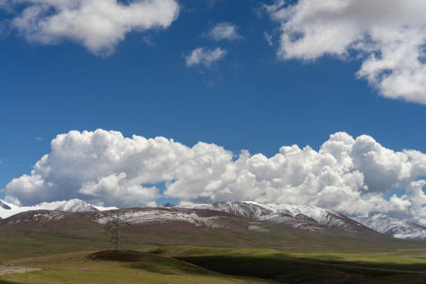 Snow-capped mountains and meadows on the plateau under blue sky and white clouds