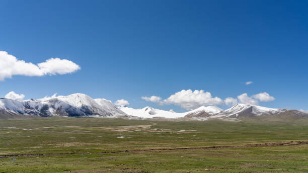istock Snow-capped mountains and meadows on the plateau under blue sky and white clouds 2158700402