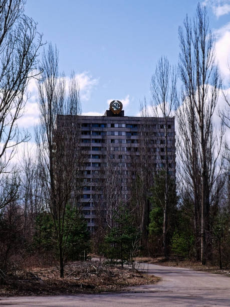istock A tall building with many windows stands behind bare trees; a path leads towards it. 2158702329
