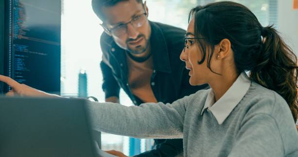 Closeup of tech team professionals collaborate discuss software development strategies in modern office. Software developer, artificial intelligence and programming.