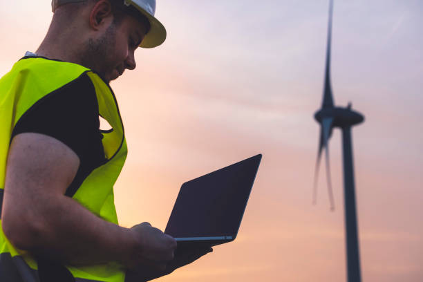 istock Worker with laptop near wind turbine at sunset 2158703179