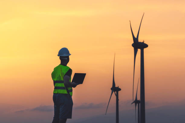 istock Engineer with laptop and wind turbines at sunset 2158703184